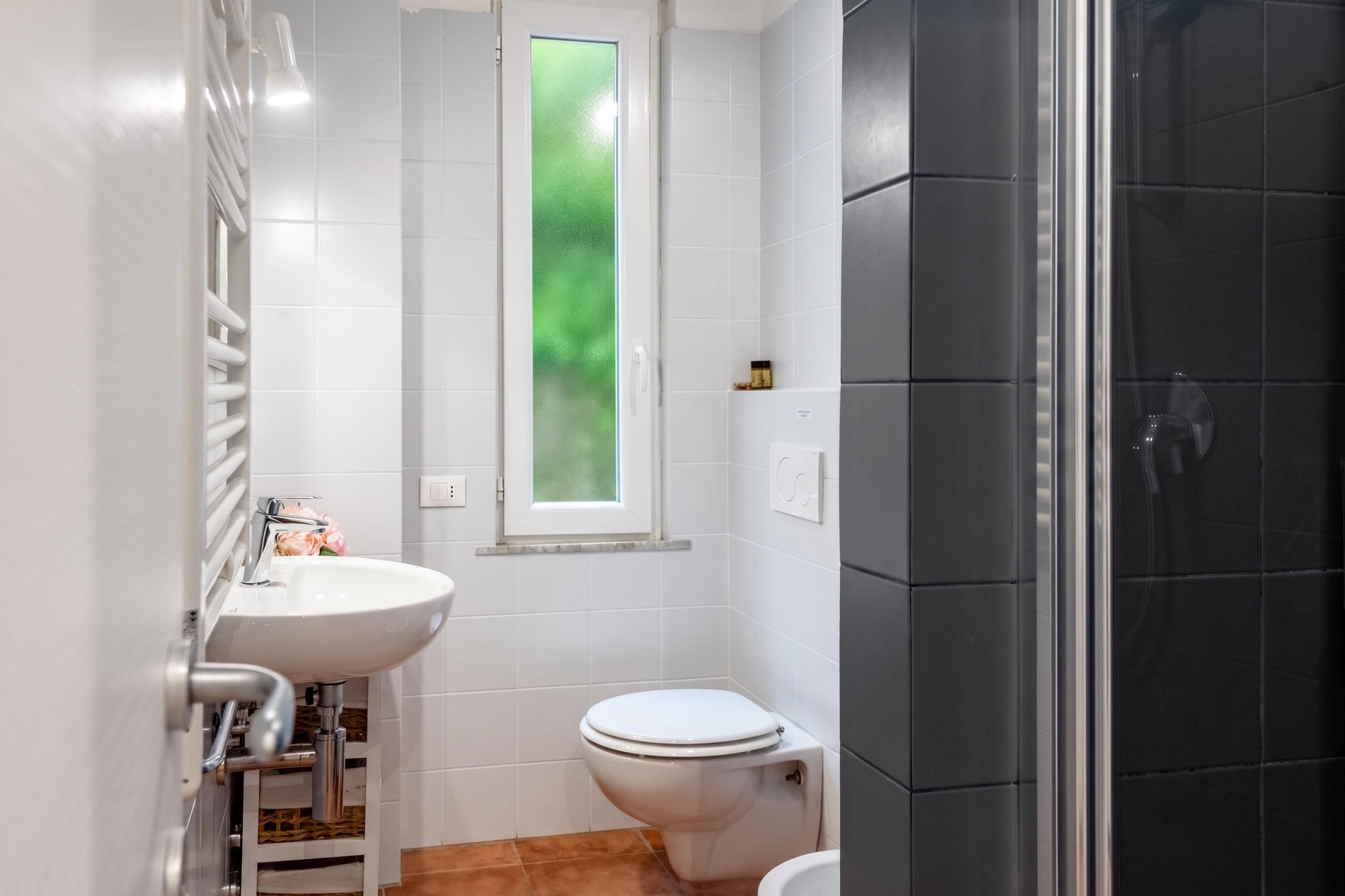 Een badkamer met een wit wastafelmeubel, toilet en douche.