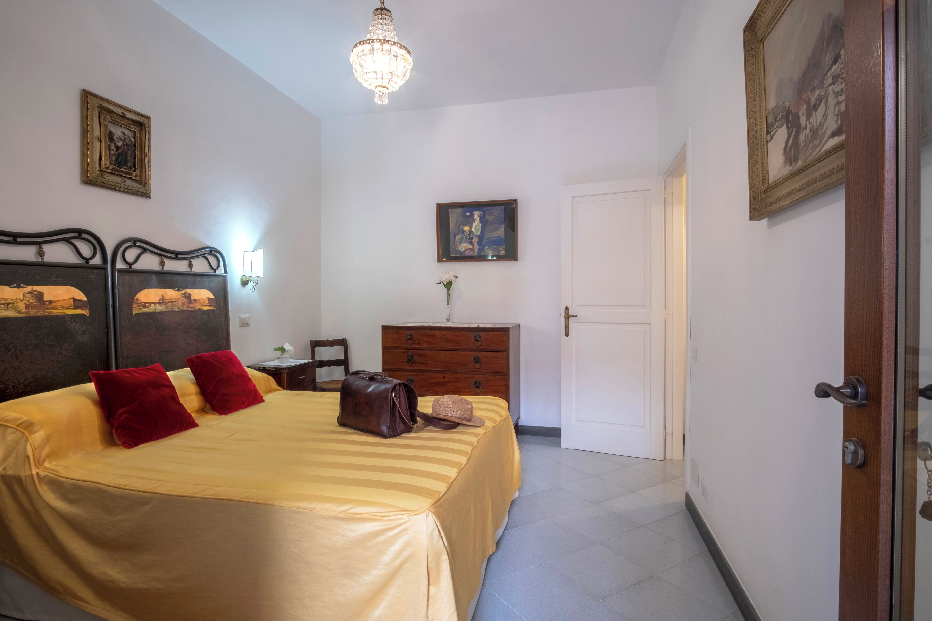 Una habitación de hotel con cama, tocador, candelabro y puerta.