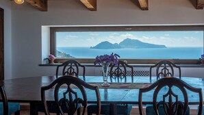 A dining area with a large window overlooking a mountainous landscape. - Torre Cangiani (Massa Lubrense)