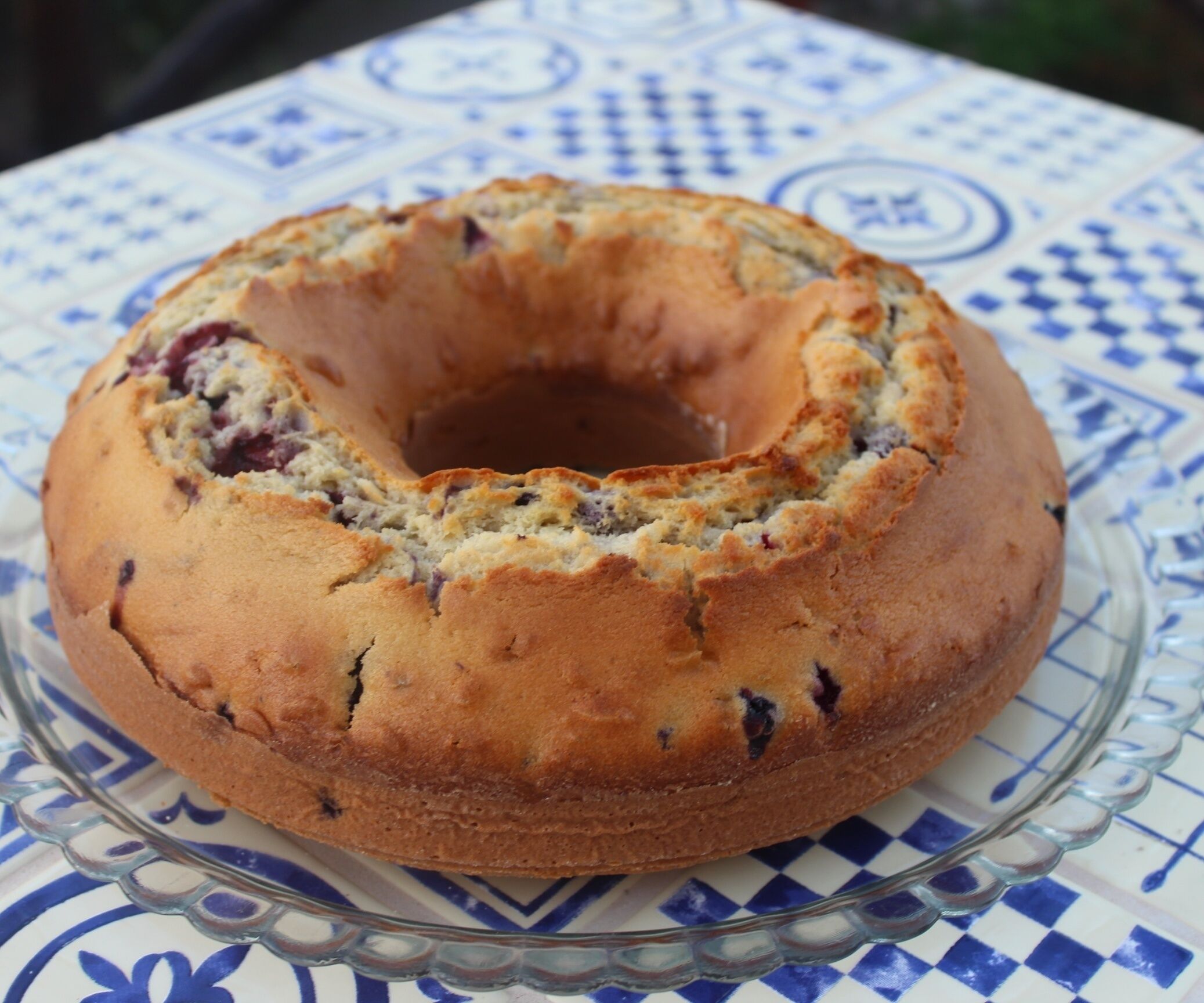 Un gâteau rond avec un trou au centre, posé sur un présentoir à gâteaux en verre.