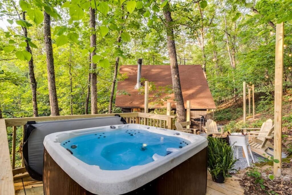Un bain à remous sur une terrasse en bois, entouré d’arbres.
