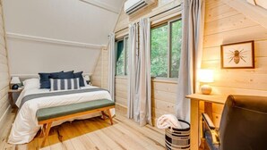 Een knus slaapkamer met een bed, nachtkastje, lamp en een raam met gordijnen.
