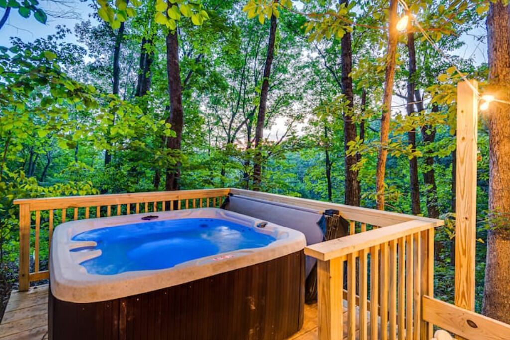 A hot tub on a wooden deck surrounded by a forest.