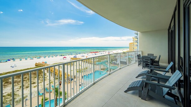 Un balcon avec vue sur la plage, des chaises longues et un espace piscine.