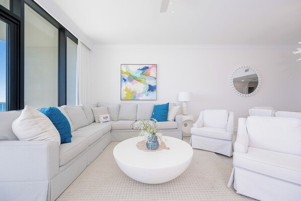 A modern living room with a sectional sofa, a round coffee table, and a large abstract painting.