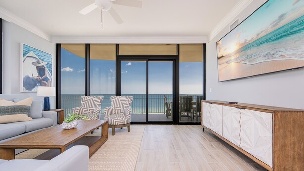A spacious living room with a large window, a ceiling fan, a sofa, a coffee table, and a cabinet.
