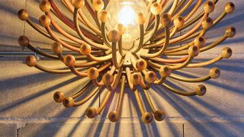 Un candelabro con múltiples brazos y bombillas esféricas frente a una pared con textura.