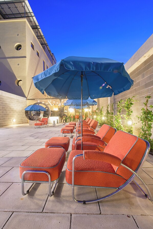 Outdoor seating with umbrellas, a brick wall, and a building in the background.