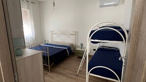 A small, well-lit room with two bunk beds, a desk, and a wardrobe.