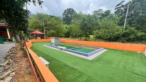 A pool area with artificial grass, a tiled pool, and an orange safety barrier. - Capital O 91152 Jerot Dusun Campsite (Yan)