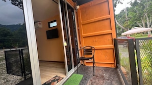 A room with a sliding glass door, a small TV, and a chair. - Capital O 91152 Jerot Dusun Campsite (Yan)