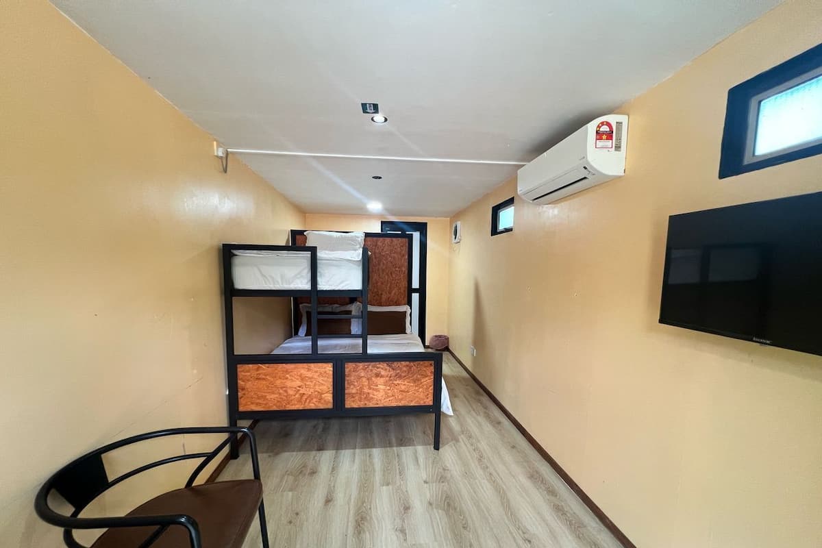 A narrow hallway with bunk beds, a chair, and a mounted TV.