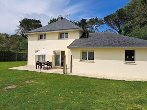 Uma casa de dois andares com um pátio, uma área de estar coberta ao ar livre e uma janela grande.