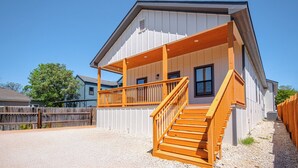 Un bâtiment à deux étages doté d’un porche couvert et d’un escalier en bois.