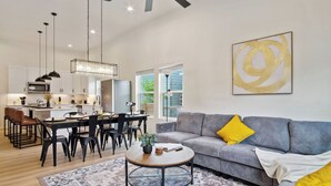 A modern living room with a grey sofa, a coffee table, and a dining area with chairs and a table.