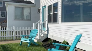 A white house with a white picket fence and two turquoise Adirondack chairs in the front yard. - Spectacular Ocean Sunsets I Pet Friendly (Weymouth)