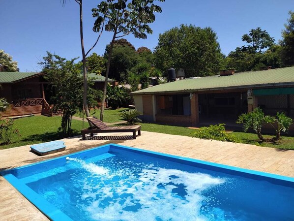 Une piscine rectangulaire dotée d’une terrasse en bois et de chaises longues.