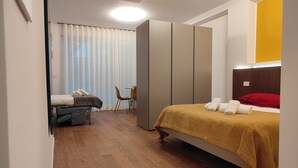 A bedroom with a bed, a chair, a wardrobe, and a desk. - CconfortHotels Maison 104 (Bari)