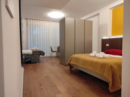 A bedroom with a bed, a chair, a wardrobe, and a desk.