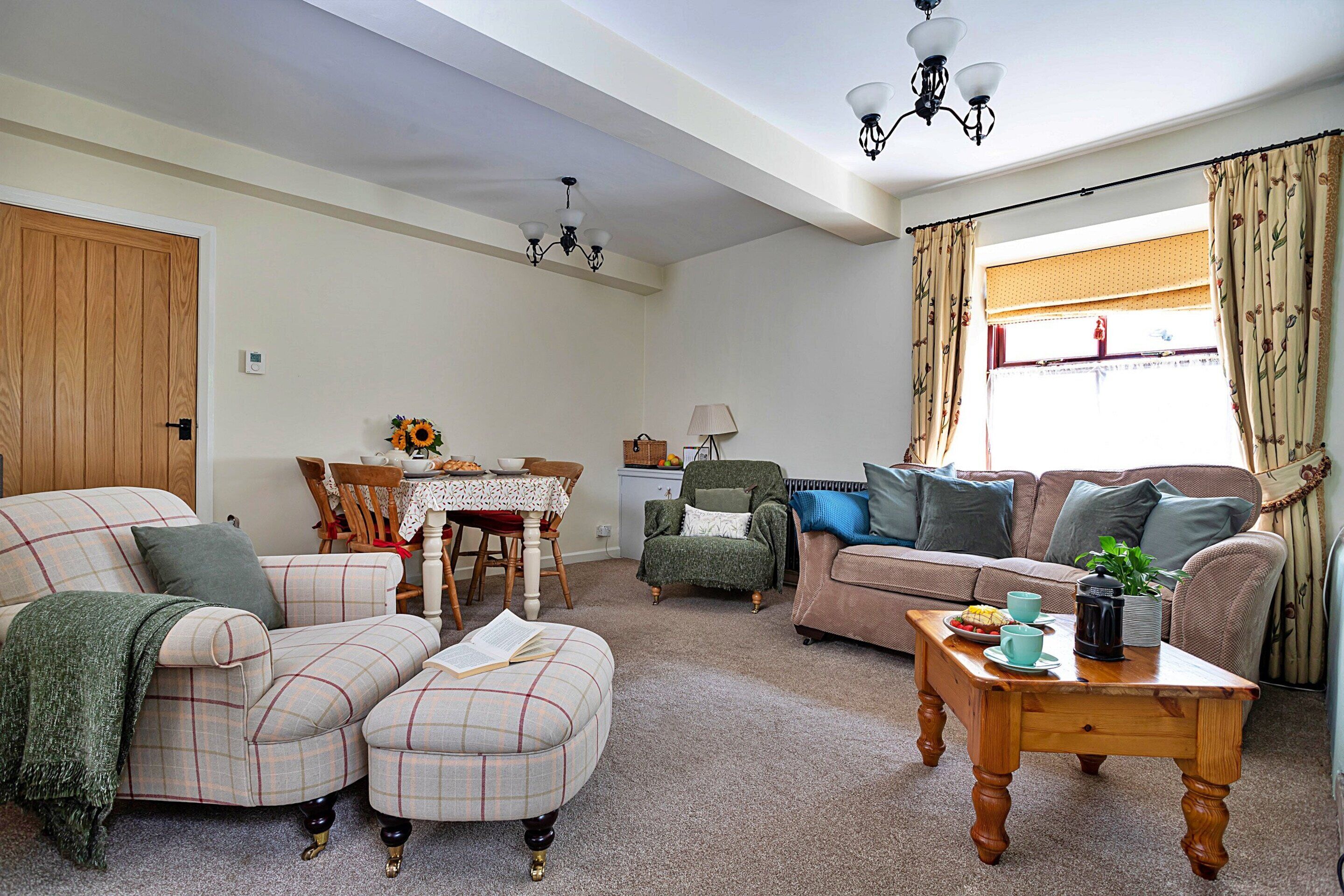 A living room with a sofa, armchair, ottoman, coffee table, and a dining area with a table and chairs.