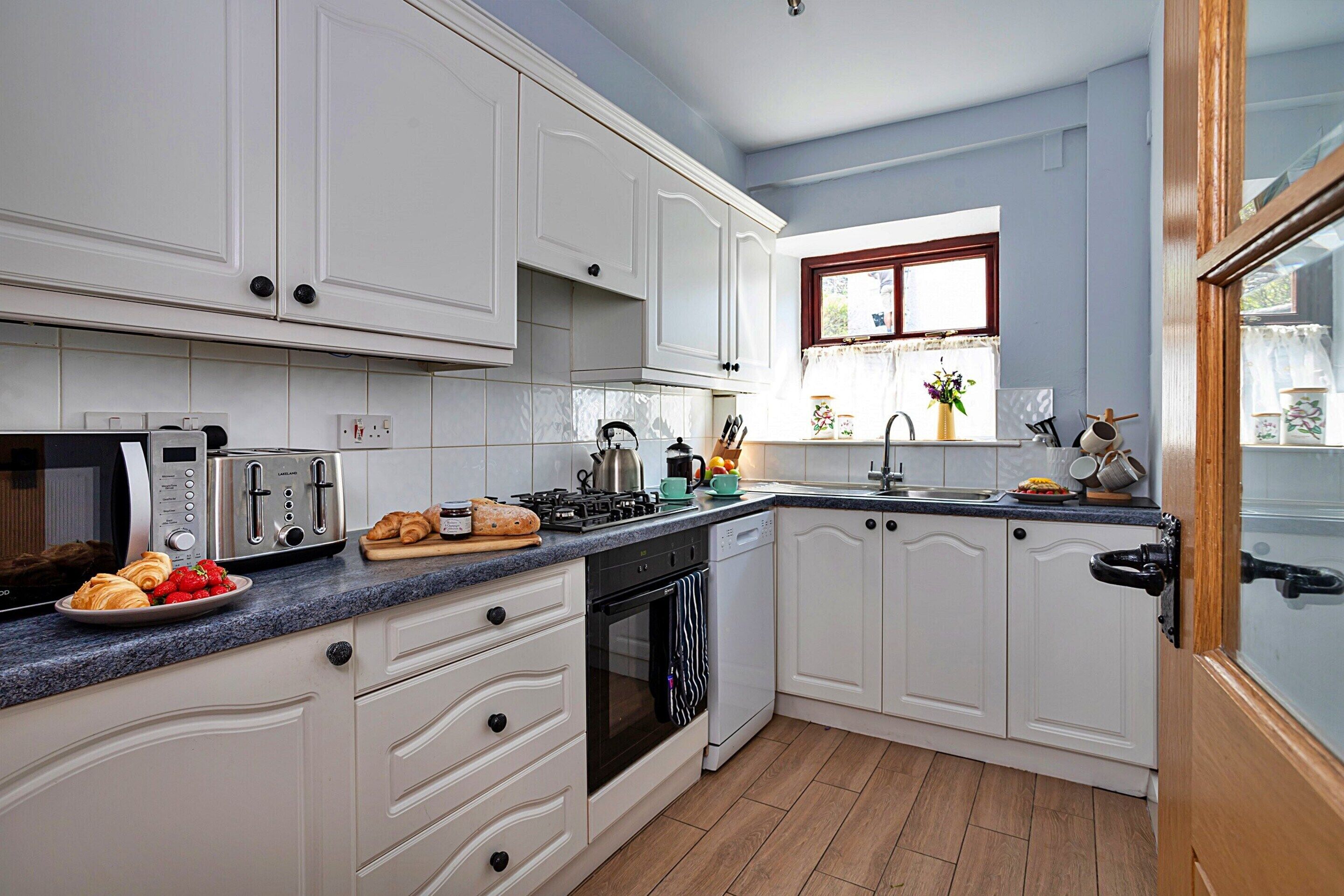A kitchen with white cabinets, a microwave, toaster, and a sink.