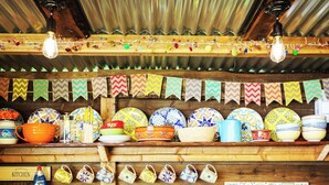 Una cucina con scaffali in legno, piatti colorati e diversi utensili da cucina.
