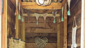 Interno di una baita di legno con ripiano che contiene articoli da toilette, una decorazione a forma di cuore e un cesto appeso.