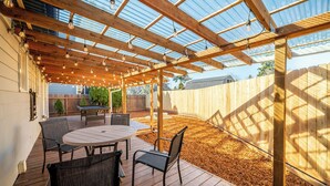 An outdoor patio with a wooden pergola, a round table, and chairs. - PDX Stay w/BBQ, Firepit & Pool Table (Portland)