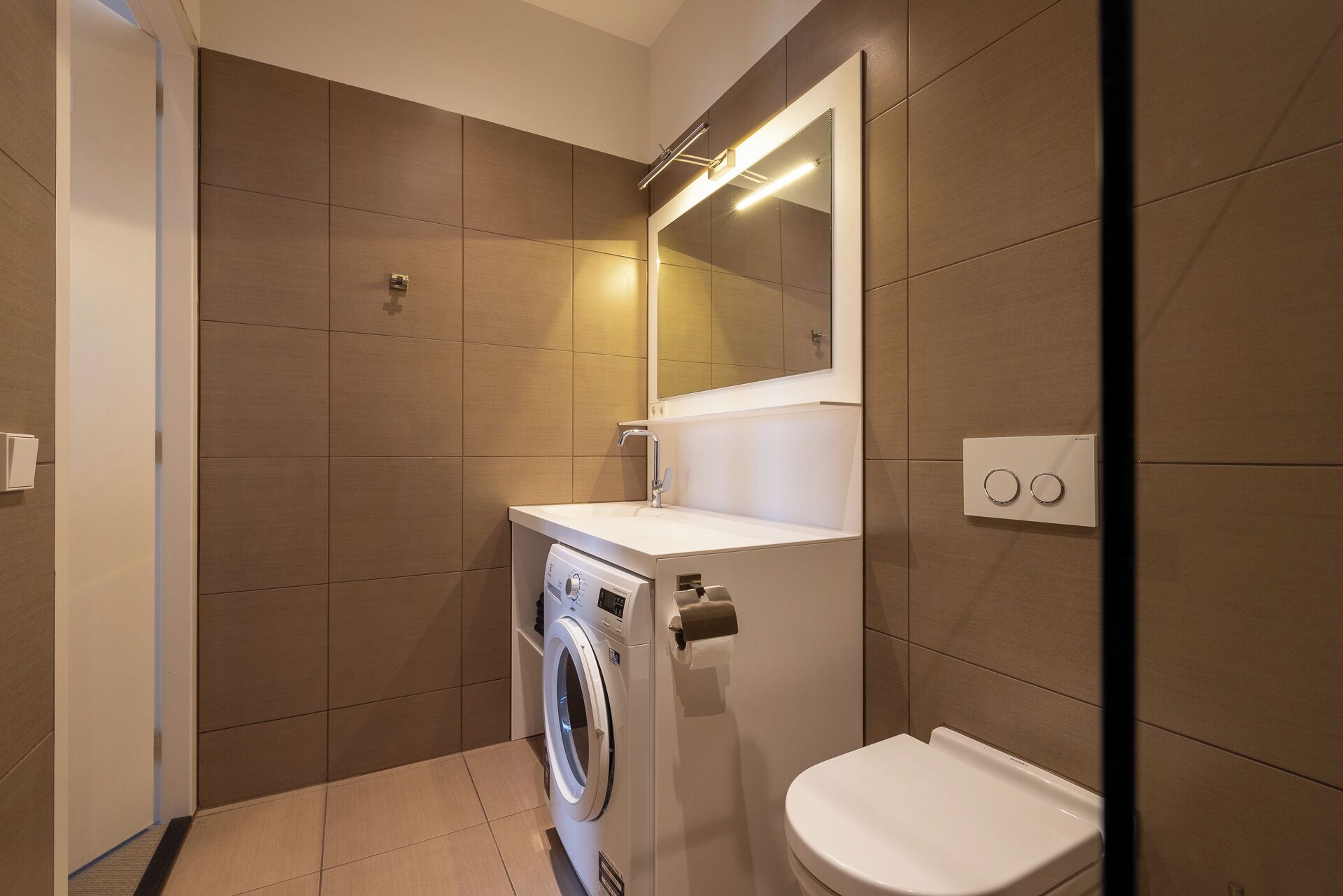 Un baño pequeño con lavadora, inodoro y espejo.