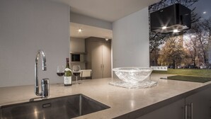Una cucina moderna con lavandino in acciaio inox, una bottiglia di vino e un bicchiere sul piano di lavoro.