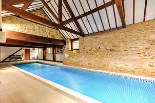 Una piscina interior con paredes de piedra y vigas de madera.