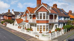 A Victorian-style house with a bay window, multiple chimneys, and a white picket fence. - Apartment in Brighton Near the Beach (Brighton)