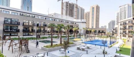 Un moderno edificio residencial con jardín en la azotea, mobiliario exterior y una piscina.