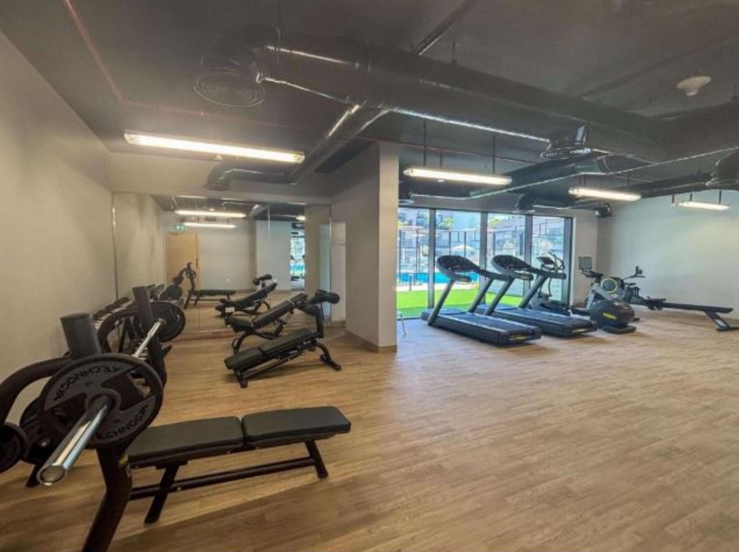 Un gimnasio con cintas de correr, bancos de pesas y equipo de ejercicio.