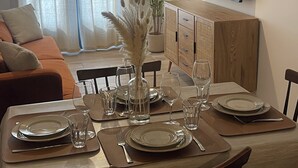 A dining area with a table set for four, a sofa, a television, and a potted plant. - Small village house (Bastelica)