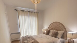 A bedroom with a bed, a bedside table with a lamp, a ceiling light fixture, and a window with curtains. - Small village house (Bastelica)
