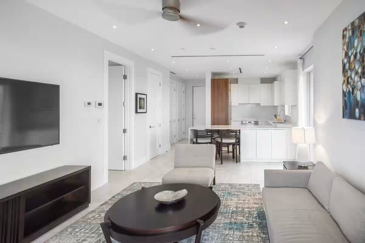 Una sala de estar moderna con una televisión de pantalla plana, una mesa redonda de centro y un sofá.