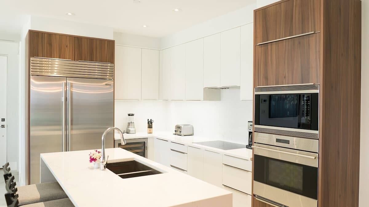 Una cocina moderna con electrodomésticos de acero inoxidable, armarios blancos y una isla central con lavamanos.