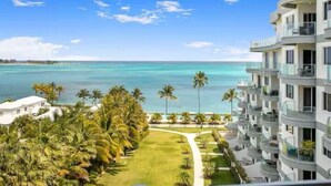 Ein Strandhotel mit freiem Blick auf den Ozean, Palmen und einem gepflegten Rasen.