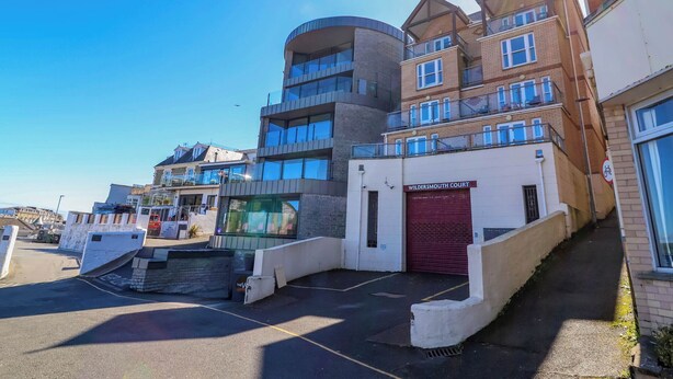 A multi-story building with a prominent red garage door labeled "WILDERMOUTH COURT". - 6 Wildersmouth Court Apartments (Ilfracombe)