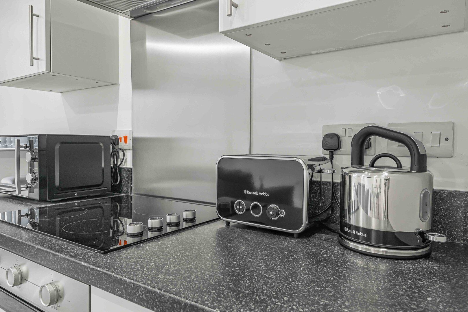 A modern kitchen with a black induction cooktop, a toaster, and a kettle.