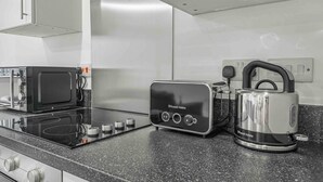 Una cocina moderna con tope de inducción negro, un tostador y un hervidor.