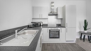 Een moderne keuken met een spoelbak, broodrooster, waterkoker, fornuis, oven en kastjes.