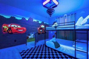 Quarto com cama beliche, piso xadrez e decoração de carro neon.