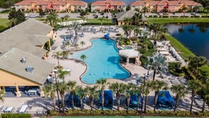 A resort with a central swimming pool, multiple buildings, and a lake.