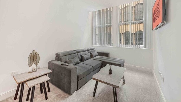 A modern living room with a grey sectional sofa, a small table, and a decorative metal piece on the floor.