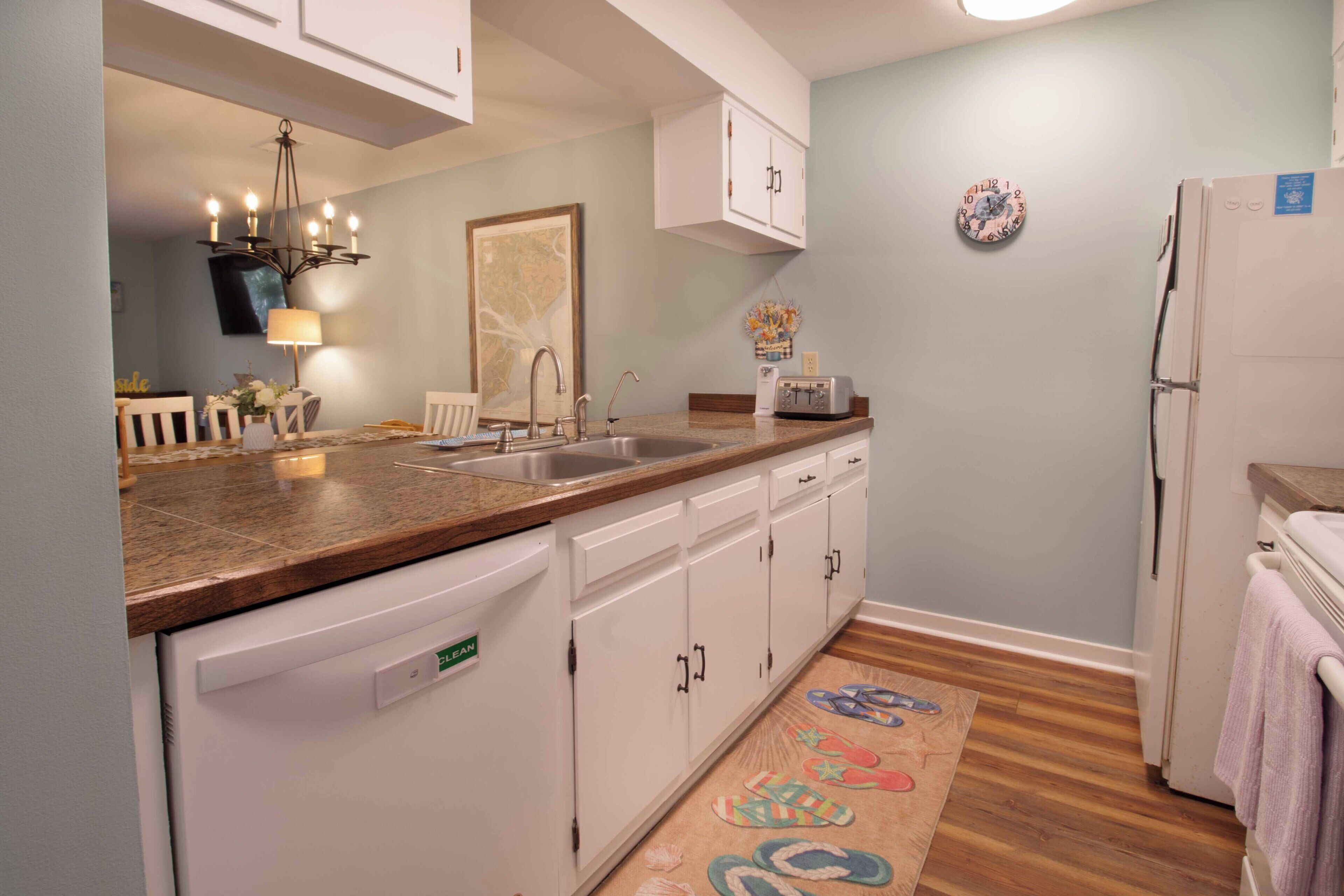 A kitchen with white cabinets, a dishwasher, a sink, and a refrigerator.