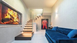 A modern interior with a fireplace, a blue sofa, and a staircase. - Exclusive Florence Getaway with Jacuzzi, Terraces & Concierge Services (Firenze)