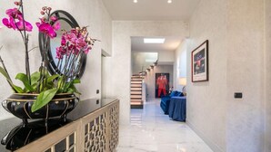 A hallway with a marble floor, a decorative black vase with orchids, a mirror, and a blue table with a lamp. - Exclusive Florence Getaway with Jacuzzi, Terraces & Concierge Services (Firenze)