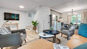 Uma sala de estar moderna com um sofá, poltronas, uma mesa de centro e uma TV fixada na parede.